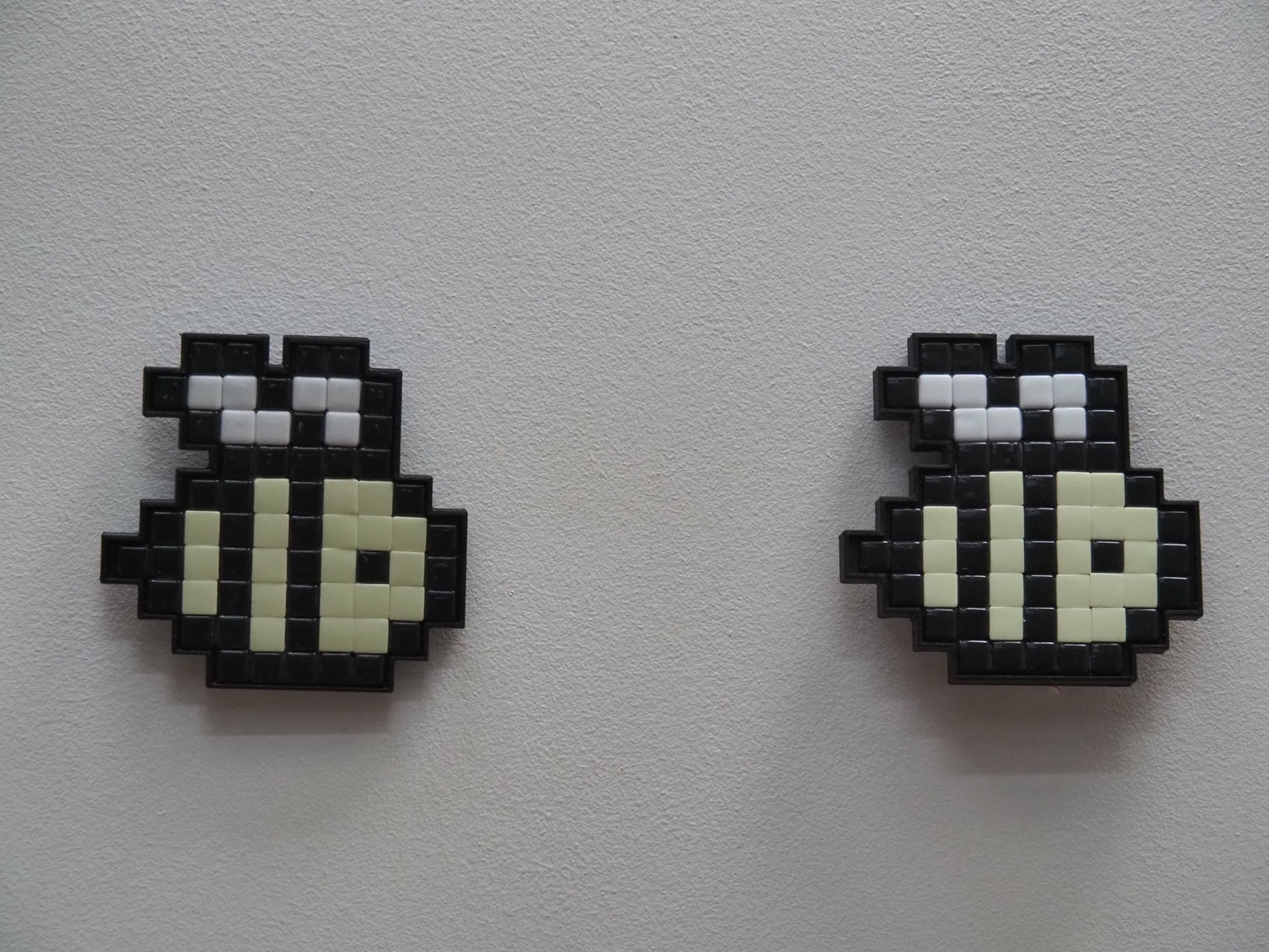 Two pixelated beess on a light gray background