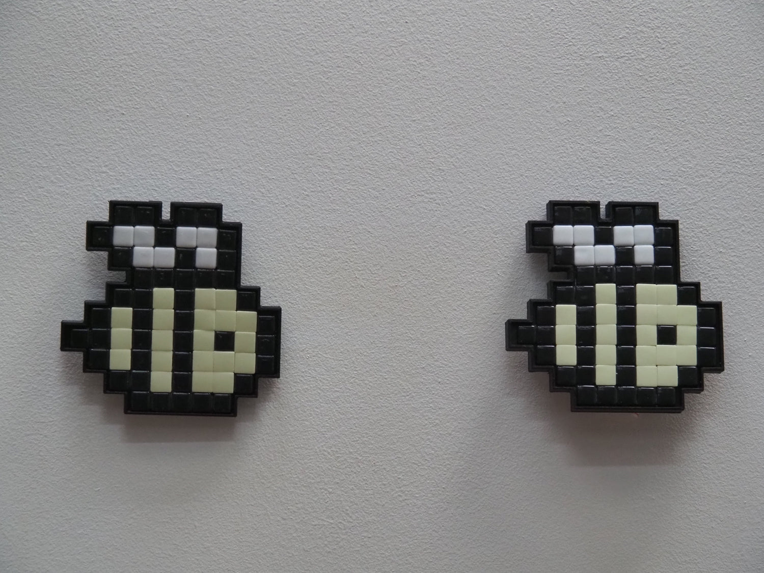 Two pixelated beess on a light gray background